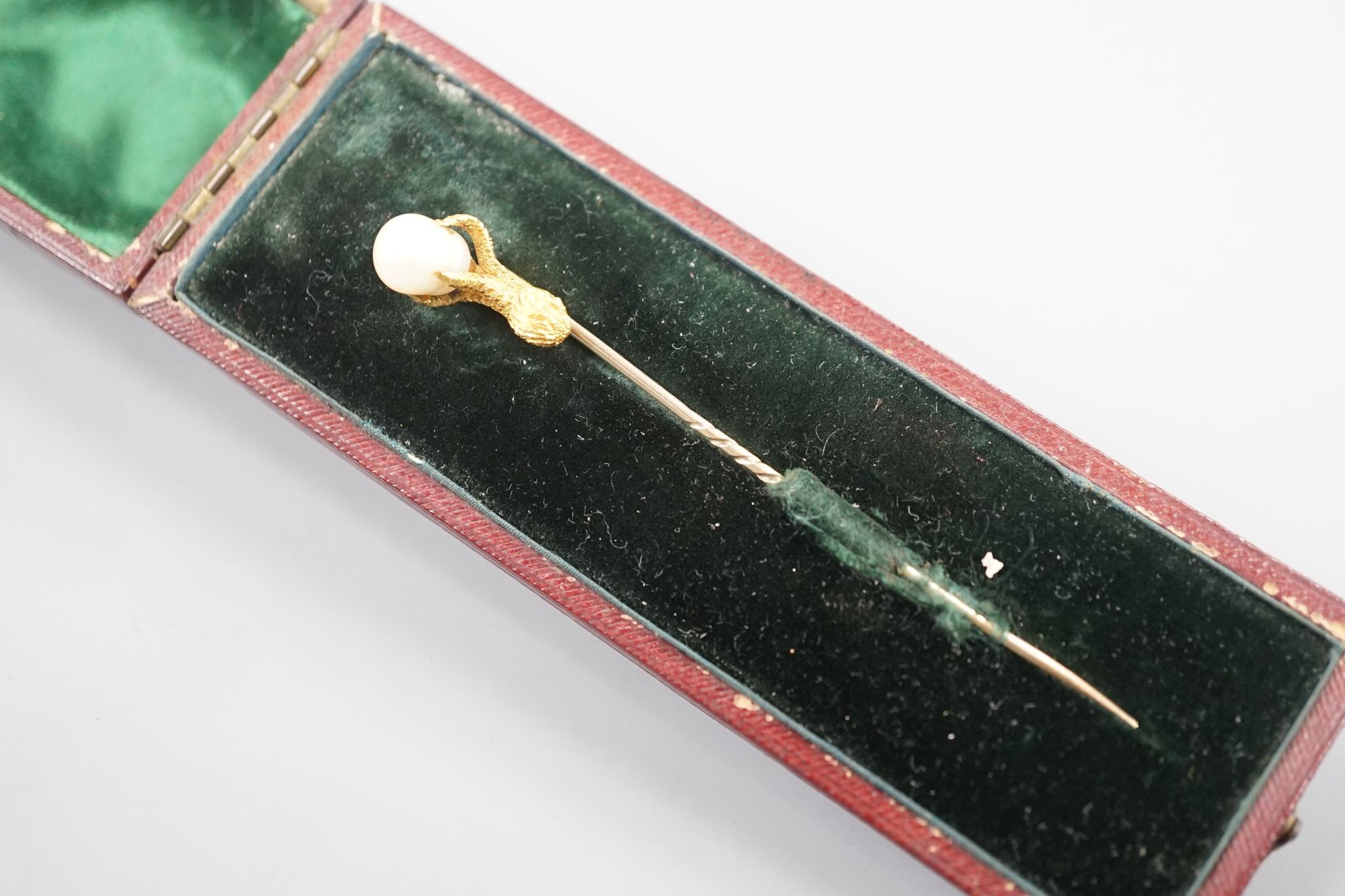 A 19th century yellow metal stick pin, the terminal modelled as an eagle's claw grasping a baroque pearl, 78mm, gross weight 3.3 grams, with box.
